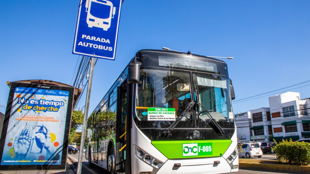 Autobús del corredor Núñez de Cáceres junto a una parada señalizada en Santo Domingo.